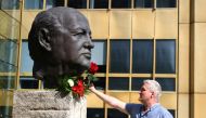 A man places a rose on a sculpture of Mikhail Gorbachev in memory of the final leader of the Soviet Union, at the 