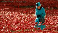 Britain's Queen Elizabeth II walks through a field of ceramic poppies at the Tower of London in London, Britain, on October 16, 2014. (REUTERS/Luke MacGregor)