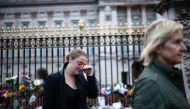 A person reacts near floral tributes placed at Buckingham Palace, following the passing of Queen Elizabeth, in London, Britain, September 9, 2022. REUTERS/Henry Nicholls