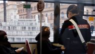 A Carabiniere checks a passenger's coronavirus disease (COVID-19) health pass, known as a Green Pass, aboard a bus the day the government restricts access of unvaccinated to indoor venues, in Rome, Italy December 6, 2021. Picture taken through glass. REUTERS/Yara Nardi
