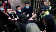 A man is pulled at the gate of the Chinese consulate after a demonstration against China's President Xi Jinping, in Manchester, Britain, on October 16, 2022. Matthew Leung/The Chaser News/Handout via REUTERS