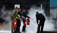 Members of the military and UK Border Force extinguish a fire from a petrol bomb, targeting the Border Force centre in Dover, Britain, October 30, 2022. (REUTERS/Peter Nicholls)