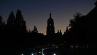 Vehicles drive along a street with the St. Sophia Cathedral silhouetted in the background, as the city is plunged into near darkness following a military strike that partially brought down the power infrastructure, in Kyiv, on October 31, 2022. (Sergei SUPINSKY / AFP)