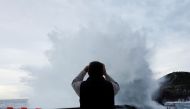 A man takes photographs as large waves crash against a breakwater in Lekeitio, Spain, November 7, 2022. (REUTERS/Vincent West)