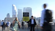 Workers pass by a sales person as they walk towards the City of London financial district as they cross London Bridge during the morning rush hour in London, Britain, on September 8, 2021. File photo / Reuters
