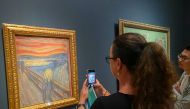 Picture taken on August 3, 2022 shows a visitor taking pictures of Edvard Munch's iconic painting 