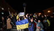People hold a Ukrainian flag and a slogan which reads 