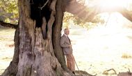 In this handout image issued by Buckingham Palace on November 14, 2022, Britain's King Charles III poses for a photograph with an ancient oak tree in Windsor Great Park to mark his appointment as Ranger of the Park. (Photo by CHRIS JACKSON / BUCKINGHAM PALACE / AFP)