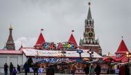 People walk past the Christmas fair on Red square near the Spasskaya tower of the Kremlin and the Saint Basil Cathedral in Moscow on November 28, 2022. (Photo by Yuri KADOBNOV / AFP)