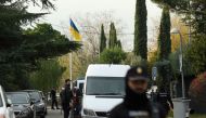 Spanish policemen stand next to a Ukrainian flag while securing the area after a letter bomb explosion at the Ukraine's embassy in Madrid on November 30, 2022. (AFP/Oscar del Pozo)