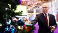 Russian President Vladimir Putin takes a child's request pinned in written form to a fir tree during an event held as part of the 'Fir Tree of Wishes' charity campaign at the Manezh Central Exhibition Hall in Moscow on December 22, 2022. (Photo by Valeriy Sharifulin / POOL / AFP)