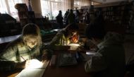 Children use flashlights as they attend a meeting of their literature club in a public library during a power outage in Irpin, northwest of Kyiv, on December 23, 2022, amid the Russian invasion of Ukraine. (Photo by Genya SAVILOV / AFP)