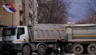 A pedestrian walks past a new road barricade set up in the divided town of Mitrovica on December 28, 2022. (Photo by Armend NIMANI / AFP)