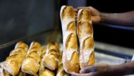 A baker shows freshly-bakedÊbaguettes at 