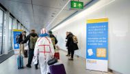 Travelers arriving from China walk past information banners and receive free Covid-19 self-test kits, at Amsterdam's Schiphol Airport on January 4, 2023. (Photo by Robin van Lonkhuijsen / ANP / AFP)