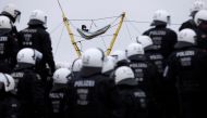 Police officers stand guard as an activist lies in a hammock connected to a structure, as activists demonstrate at Luetzerath, a village that is about to be demolished to allow for the expansion of the Garzweiler open-cast lignite mine of Germany's utility RWE, Germany, January 10, 2023. (REUTERS/Thilo Schmuelgen)