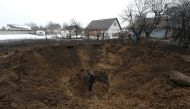 A man stands inside a crater left by a Russian missile, amid Russia's attack on Ukraine, in the village of Kopyliv, Kyiv region, Ukraine January 14, 2023. Reuters/Valentyn Ogirenko