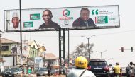 Motorcycle taxi drivers carry passengers as they ride past campaign posters of Peter Obi, presidential candidate of the Labour Party, in Ibadan, south-west of Nigeria on January 17, 2023. (Photo by Samuel Alabi / AFP)