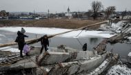 In this file photo taken on February 1, 2023 People walk on a destroyed bridge to cross a canal towards the disputed area in Bakhmut, amid the Russian invasion of Ukraine. Photo by YASUYOSHI CHIBA / AFP