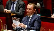 French Labour Minister Olivier Dussopt looks at a political leaflet of President Emmanuel Macron candidate for the 2022 French presidential election on pension reform during a session to discuss on the government's pension reform plan at the National Assembly, French Parliament lower house, in Paris, on February 13, 2023. (Photo by Ludovic MARIN / AFP)