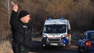 A security official gestures as an ambulance moves on the outskirts of the village of Lokorsko, some 20 kilometres (12 miles) north-east of Sofia, after the discovery of eighteen dead migrants in the rear of an abandoned truck. (Photo by NIKOLAY DOYCHINOV / AFP)