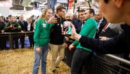 French President Emmanuel Macron poses with visitors for photograph as he visits the 59th edition of the International Agriculture Fair on its inauguration day in Paris, on February 25, 2023. (Photo by CHRISTIAN HARTMANN / POOL / AFP)
