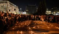People hold candles and black balloons during a silent demonstration in front of the Greek Parliament in Athens, on March 3, 2023 (Photo by Louisa Gouliamaki / AFP)