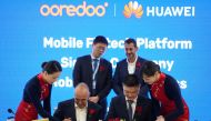 Ooredoo and Huawei officials sing the agreement.