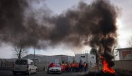 Unionists stand near a bonfire as they block access to the Storengy Site as they protest against the government's proposed pensions overhaul, which includes raising the minimum retirement age to 64 from 62 and increasing the number of years people have to make contributions for a full pension, in Chemery, central France, on March 17, 2023.  (Photo by GUILLAUME SOUVANT / AFP)