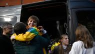 Denys Zaporozhchenko (left) meets his children Nikita, Yana and Dayana (right) after the bus delivering them and more than a dozen other children back from Russian-held territory arrived in Kyiv on March 22, 2023.  (Photo by SERGEI CHUZAVKOV / AFP)