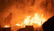 A firefighter tries to extinguish a fire during a demonstration, a week after the government pushed a pensions reform through parliament without a vote, using the article 49.3 of the constitution, in Paris on March 23, 2023. (Photo by Anna Kurth / AFP)