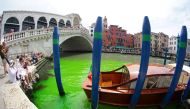 A photo taken and made available on May 28, 2023 by Italian news agency Ansa, shows fluorescent green waters below the Rialto Bridge in Venice's Grand Canal. (Photo by Stringer / Ansa / AFP) 