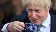 (FILES) In this file photo taken on May 12, 2022 Britain's then prime minister Boris Johnson drinks from a cup as he talks with local business leaders after hosting a cabinet away day in Stoke-on-Trent, central England, on May 12, 2022. (Photo by Oli SCARFF / POOL / AFP)
