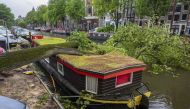A storm damaged tree lies on a canal boat on the Keizersgracht in the centre of Amsterdam on July 5, 2023, after winds of ' Storm Poly' struck north Holland where a 'code red' was issued as an extreme weather warning. (Photo by Evert Elzinga / ANP / AFP)