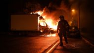 A French anti-riot police officer walk past a burning truck in Nantes, western France on early July 1, 2023. Photo by Sebastien SALOM-GOMIS / AFP


