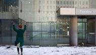 A woman throws snow in the air at a plaza in front of an office building in Johannesburg on July 10, 2023. Photo by Wikus de Wet / AFP