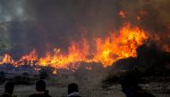Locals watch the wildfires near the village of Vati, just north of the coastal town Gennadi, in the southern part of the Greek island of Rhodes on July 25, 2023. (Photo by Angelos Tzortzinis / AFP)