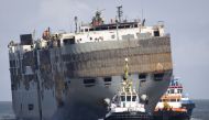 People look at the Panamanian-registered car carrier ship Fremantle Highway, from Eemshaven, on August 3, 2023 as it is being towed to a new location after a fire broke out late on July 25, 2023, killing one crew member, and prompting a massive effort to extinguish the flames. Photo by Vincent Jannink / ANP / AFP