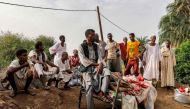 People sit outdoors on salvaged furniture in an area devastated by floods in al-Sagai north of Omdurman on August 6, 2023. (Photo by AFP)
