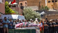 People recite a prayer in front of the bodies of victims killed in an earthquake in Moulay Brahim, Al Haouz province, on September 9, 2023.  Photo by FADEL SENNA / AFP