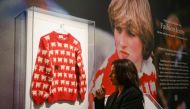 A staff member poses with the 'Black Sheep Jumper' designed by Sally Muir and Joanna Osborne and worn on several occasions by Britain's late Princess Diana, during a press view at Sotheby's auction house in London on July 17, 2023. (Photo by Daniel LEAL / AFP)