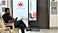A man checks his mobile as he sits outside an Air Canada regional office in New Delhi on September 20, 2023. (Photo by Arun Sankar / AFP)