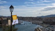 :This photograph taken on September 22, 2023, shows a view of the Old Port (R) of Marseille and of the Saint-Jean Fort, with a Vatican flag held on a lamp post, prior to the Pope's visit to the city. Pope Francis heads to Marseille for a two-day visit focused on the Mediterranean and migration, bringing a message of tolerance amid bitter debate over how Europe manages asylum seekers. (Photo by CHRISTOPHE SIMON / AFP)
