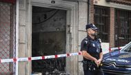 A police officer stands guard next to a building where four minors were killed in a fire in Vigo on October 11, 2023. Photo by MIGUEL RIOPA / AFP