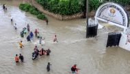 Pedestrians try to pass a flooded street following heavy rains at Kiembeni district in Mombasa on November 17, 2023. (Photo by STRINGER / AFP)