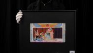 An employee holds a drawing by late French cartoonist Albert Uderzo, which appeared on the original cover of 
