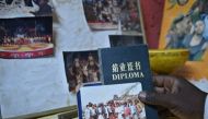 Mathias Kavita shows his diploma of acrobatic study from China and a photo of his time in China at Sarakasi dome in Nairobi, Kenya, on Nov. 11, 2023. (Xinhua/Han Xu)

