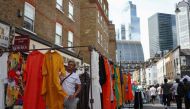 Shoppers browse stalls in Petticoat Lane Market, against the backdrop of The City of London financial district in London on August 11, 2023.  Photo by HENRY NICHOLLS / AFP