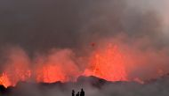 People watch flowing lava during an volcanic eruption near Litli Hrutur, south-west of Reykjavik in Iceland on July 10, 2023. (Photo by Kristinn Magnusson / AFP)