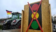 A tractor decorated with a German flag is seen next to a crossed out traffic light sign on January 15, 2024 in Berlin. (Photo by John MacDougall / AFP)
